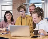 Zespół pracuje nad projektem, dyskutując przy laptopie. Może to być ich **praca** jako **ratownik KPP**.
