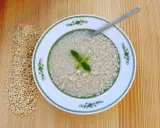 Eine Schüssel mit Trahana, garniert mit Minze, neben einem Haufen getrockneter Trahana. Ein Löffel liegt in der Schüssel.