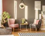 Un angolo relax casa con due poltrone, un tavolino con fiori e libri, e una libreria. Luce solare crea un'atmosfera accogliente.