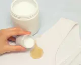 Mano aplica polvo blanqueador sobre mancha amarilla en ropa blanca. ¡Descubre cómo blanquear ropa blanca fácilmente!