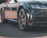 Błyszczące, czarne auto sportowe z felgami i widocznym rantem ochronnym opony.