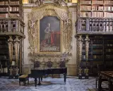 Prachtvolle Coimbra Bibliothek mit einem Flügel und einem Porträt.