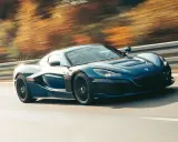 Blauer Rimac Nevera rast auf einer Straße, die Bäume im Hintergrund verschwimmen. Ein Beweis für die unglaubliche rimac nevera top speed.