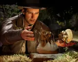 Indiana Jones i Wielki Krąg: archeolog z kapeluszem i skórzaną kurtką trzyma złoty artefakt w kształcie skarabeusza.