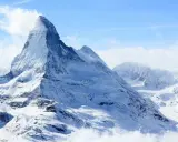 Majestatyczny, ośnieżony szczyt Matterhorn, jeden z najwyższych szczytów Europy, wyłania się z chmur.