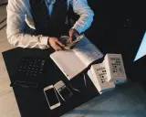 Mężczyzna liczy pieniądze, obok leżą telefony i kalkulator. To może być pomocne, jak udowodnić pochodzenie pieniędzy.