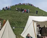 Ludzie wchodzą na Kopiec Kraka, a u jego podnóża rozstawiono historyczne namioty.