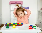 Bambina con puzzle e colori, un'immagine che fa riflettere su cos'è l'asperger e come supportare i bambini.