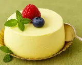 Délicieuse panna cotta mangue, garnie d'une framboise, d'une myrtille et de feuilles de menthe, prête à être dégustée avec une cuillère.