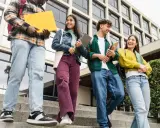 Studenci idą po schodach, rozmawiając i śmiejąc się. Czy ich wysoka średnia pozwoli im zdobyć stypendium?