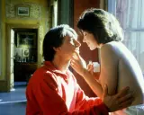 Intymna scena z filmu erotycznego dla dwojga. Kobieta delikatnie dotyka twarzy mężczyzny, który ubrany jest w czerwoną bluzę.