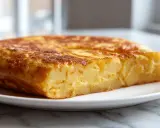 Złocista tortilla z airfryer, pyszna i prosta w przygotowaniu, z widocznymi kawałkami ziemniaków.