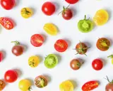 Un assortiment coloré de meilleures tomates cocktail, entières et coupées, sur fond blanc.