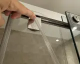 Mano insertando una goma nueva para cambiar gomas mampara ducha.