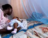 Mor och barn under myggnät, skyddade från malaria. Bali är en plats där kampen mot malaria fortsätter.