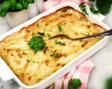 En krämig Janssons frestelse i en vit form, redo att serveras. Perfekt för ett julbord eller en mysig middag.
