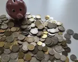 Różowe świnka-skarbonka i stos monet. Zastanawiasz się, ile kosztuje wizyta u prawnika?
