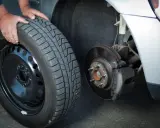 Mani che cambiano una gomma invernale, rispettando l'obbligo cambio gomme per la sicurezza stradale.