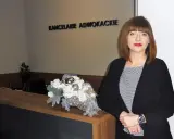 Kobieta w czarnym żakiecie przy recepcji z dekoracją kwiatową. Napis "KANCELARIE ADWOKACKIE".