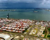 Vasto deposito di container nel porto di San Juan, Porto Rico, con navi in lontananza sotto un cielo nuvoloso.