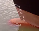 La coque d'un navire, marquée de -22 à -14, flotte sur l'eau. Le déplacement léger du bateau est visible.
