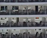 File di cabine crociera con balconi arredati con sedie e tavolini, pronte per accogliere i passeggeri.