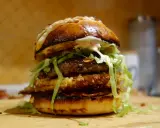 Apetyczny burger drwala przepis: podwójna wołowina, chrupiący panierowany kotlet, sałata i sos na puszczy.