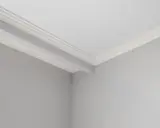 Angolo di una stanza con pareti grigie e soffitto bianco. Si nota uno stacco tra parete e soffitto con una modanatura decorativa.