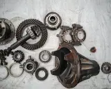 Rozłożony mechanizm różnicowy w skrzyni biegów: koła zębate, wałek atakujący, obudowa i łożyska.