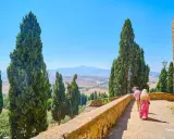 Coppia in cammino durante un tour Toscana 5 giorni, tra cipressi e colline ondulate sotto un cielo azzurro.