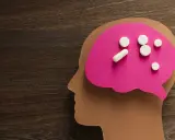 Papierowy profil głowy z różowym mózgiem, na którym leżą tabletki. Symbolizują one psychobiotyki na depresję, szukając ulgi dla umysłu.