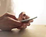 Dłonie trzymające telefon, jakby zastanawiając się, czy na odwyku można mieć telefon.