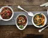Verschiedene Salate als Beilagen für ein Fondue: Linsensalat, Gemüsesalat mit Karotten und Grünkohl, sowie ein weiterer bunter Salat.