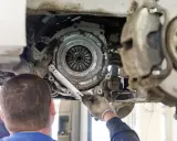 Mechanik dokonuje wymiany sprzęgła w Nissan Qashqai 1.6 benzyna. Widoczny jest mechanizm sprzęgła i narzędzia.