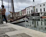 Coppia in attesa a Cesenatico, con barche d'epoca ormeggiate e il Municipio sullo sfondo. Un ricordo speciale prima di San Marino.