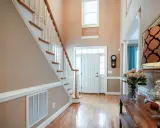 Pasillos con encanto: escalera de madera, puerta blanca y un jarrón con rosas.