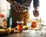 Barman przelewa płyn z shakera do drinka, tworząc kolorowe koktajle. Mieszanie alkoholi to sztuka.