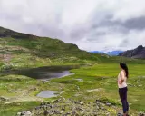Mujer admira un lago y prados verdes en el Valle de Tena, ideal para rutas de senderismo.