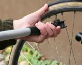 Dłoń trzyma pompkę przy wentylu koła rowerowego 29 cali, sprawdzając jakie ciśnienie w oponach rowerowych 29 cali jest optymalne.
