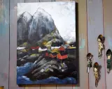 Målade landskap med röda hus vid en bergig kust. Konstverket hänger på en vägg av slitna träplankor.