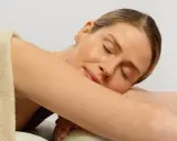 Kobieta z zamkniętymi oczami, otulona ręcznikiem, pokazuje, jak odpoczywać. Cieszy się chwilą relaksu.