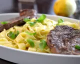 En krämig pastarätt med tagliatelle, garnerad med färsk basilika och serverad med saftig entrecote.