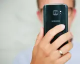 Osoba trzyma czarny telefon Samsung, pokazując tył z aparatem. Dowiedz się, jak poprawić jakość aparatu w telefonie Samsung, aby robić lepsze zdjęcia.