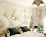 Dormitorio con papel pintado de palmeras, ideal para aprender como poner papel pintado. Cama con cojines oscuros, espejo y planta.