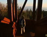 Turysta wchodzi po drewnianych schodach na wieżę widokową, podziwiając panoramę gór.