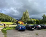Kasprowy Wierch parking pod burzowym niebem. Kilka samochodów zaparkowanych przy górskiej chatce z żółtym banerem.
