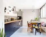 Cuisine sans placard haut, avec des meubles bas sombres, un plan de travail en bois et une table à manger.