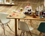 Tavolo in legno con sedie Eames House, cupcake, candele e fiori. Un'atmosfera accogliente per una festa.