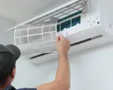 Un technicien retire un filtre sale d'une climatisation. Un entretien régulier est essentiel pour le prix et l'efficacité de votre climatisation.