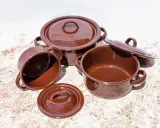 Conjunto de cazuelas de barro esmaltada en marrón. Listas para curar y preparar deliciosos guisos.